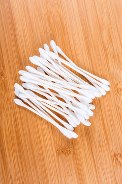 Pile of white cotton swabs isolated on wood background