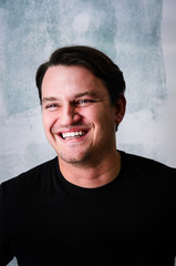 Portrait of young adult happy man agaist grunge wall