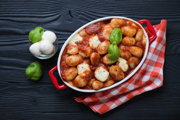 Casserole with gnocchi alla Sorrentina on a black wooden surface