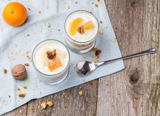 Fresh homemade dessert with biscuits, yogurt, tangerines and walnuts, served in a glass