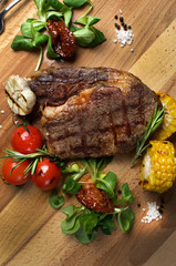 Ribeye steak with roasted vegetables on a wooden board 