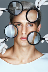 Face of beautiful man with magnifiers. Concept of rejuvenation and skin care