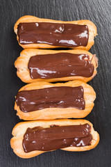 Eclairs with chocolate cream on black background.