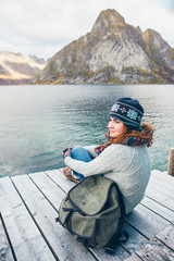 Woman traveler with a backpack sitting on a wooden pier.
