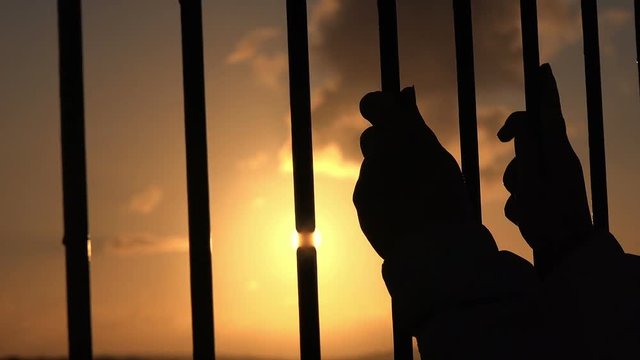 captive man prisoner in a cage craving for freedom, sunset