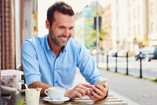 Picture of handsome man using smart phone at outdoors cafe - Powered by Adobe