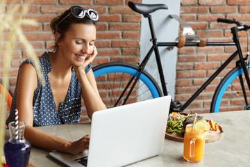 Attractive woman wearing sunglasses on her head making video call to her boyfriend, smiling shyly,...