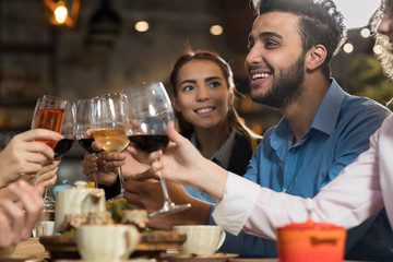Young Business People Group Drink Wine Sitting Restaurant Table, Friends Hold Glasses Clink Toasting Smiling Mix Race Men Women