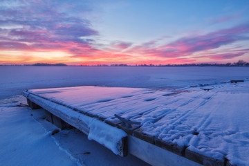 Winter Sunrise on a Snow covered Lake and Fishing Dock