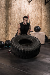 Sport Fitness Man Flipping Wheel Tire Crossfit Training, Young Healthy Guy Gym Interior