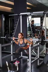 Fototapeta na wymiar Muscular young woman doing exercises on the simulator in the gym