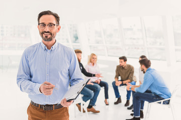 Smiling psychologist standing and holding questionnaire