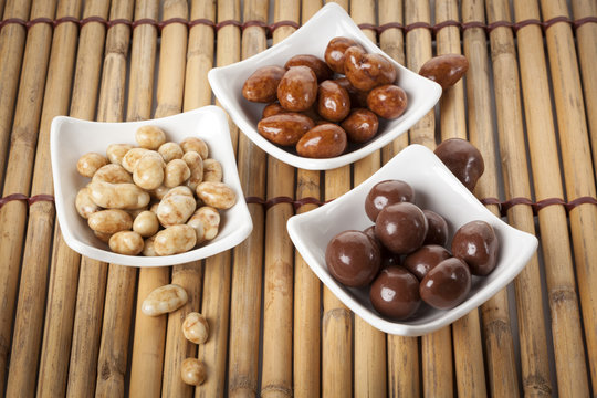 Variety of candied nuts in bowl on bamboo place mat
