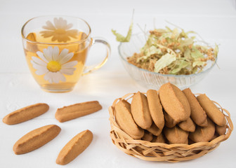 Ginger biscuits with herbal tea on a white wooden table.