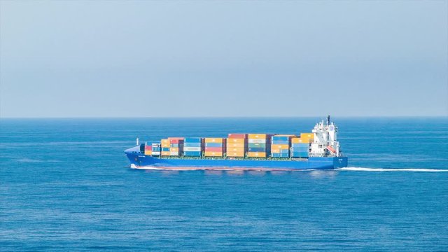 Generic Cargo Ship with Shipping Containers at Sea Sailing in Blue Ocean Water on a Sunny Day with Calm Weather Conditions