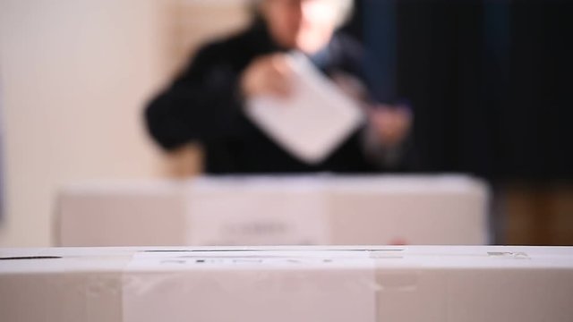 Unrecognizable people casting votes into the ballot box during elections