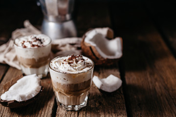 Coconut latte on a wooden table. Broken coconut. Low key food photo.