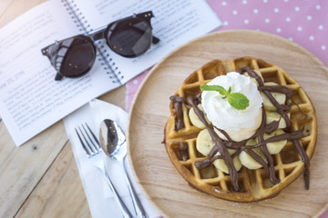 breakfast dessert, waffle with banana chocolate and whip cream topping.