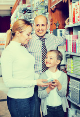 Mother and father with kid picking in pharmaceutical store
