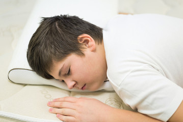 Boy teenager sleeping face down on anatomic pillow