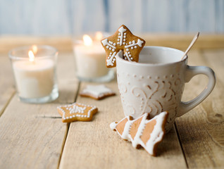 Cup of hot chocolate with gingerbread and candle.