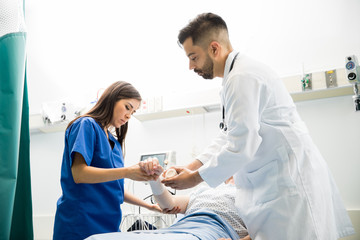 Doctors bandaging the arm of a patient in emergency room