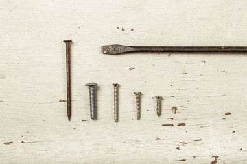 Various screws on old white wood with screwdriver, choose the right man on the right job concept
