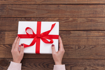 Woman holding presents gift box laid on wooden table background