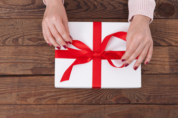 Woman holding presents gift box laid on wooden table background