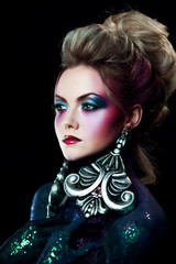 Young attractive blonde girl in bright art-makeup, high hair, body painting. Rhinestones and glitter