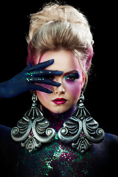Young attractive blonde girl in bright art-makeup, high hair, body painting. Rhinestones and glitter