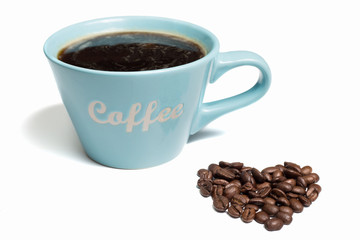 A blue cup of black coffee and a pile of coffee beans sharped like a heart on a white background