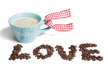 A blue cup of black coffee with foam and coffee beans spelling love on a white background