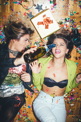 Two girls laying on the floor full of confetti and having fun