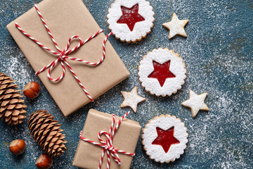 New Year or Christmas presents wrapped with ribbon Xmas holiday celebration handmade gift box and linzer Chrismas cookies with jam, fir tree cones on powdered vintage table background