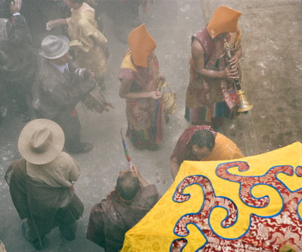 Yellow hat monks at Tibetan Buddhist new year (Lhosar), when flour thrown in the air as part of the celebrations, Samtenling monastery, Bodhnath, Kathmandu, Nepal