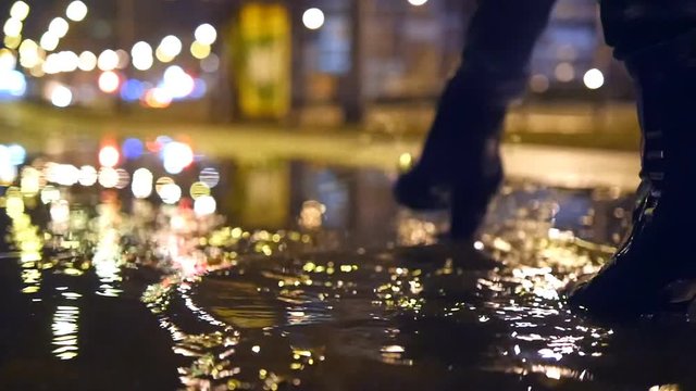 Close up slow motion shot of womans legs stepping into muddy puddle and making splash 