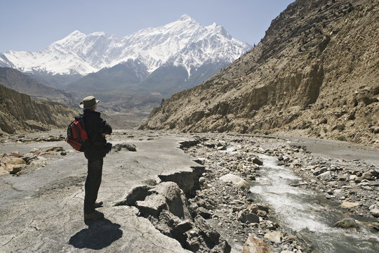 Trekker enjoys the view on the Annapurna circuit trek, Jomsom, Himalayas, Nepal. The high peak in the distance is 7021m Nilgiri, forming part of a wall known as The Grand Barrier. Model released.