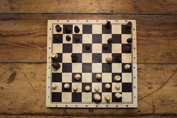 a single hand playing chess on a wooden board set on some wooden