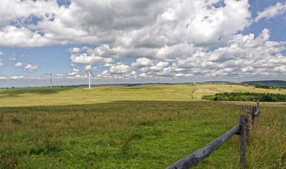 Fototapeta premium Green fields with windmills, slopes and a part of the bamboo fence