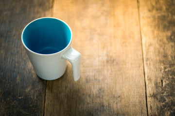 White cup inside blue colored on wooden background