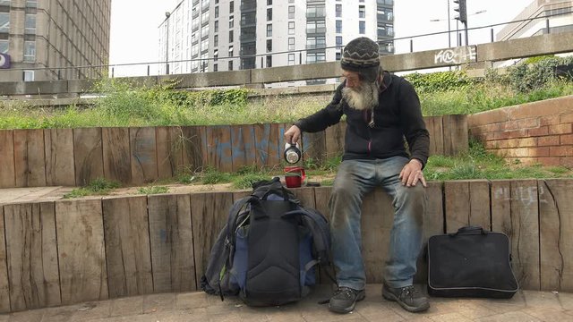 real homeless drinking hot coffee in the street: hungry old man living alone 