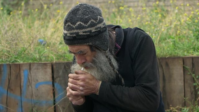 elderly homeless smoking in the street: addicted old man, ill elderly