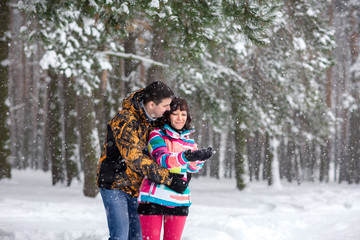Fototapeta na wymiar Winter playing, couple in colorful sport wear in winter forest