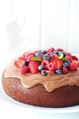 Homemade chocolate cake with berries on white wooden table
