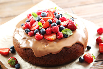 Homemade chocolate cake with berries on brown wooden table