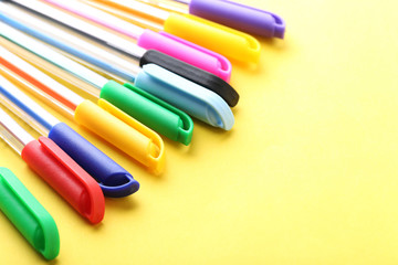 Colored pens on a yellow background