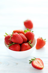 Strawberries in bowl on white wooden table