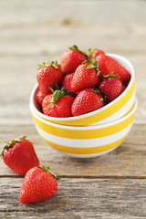 Fresh and tasty strawberries in bowl on a grey wooden table