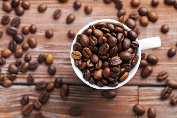 Roasted coffee beans in cup on a brown wooden table